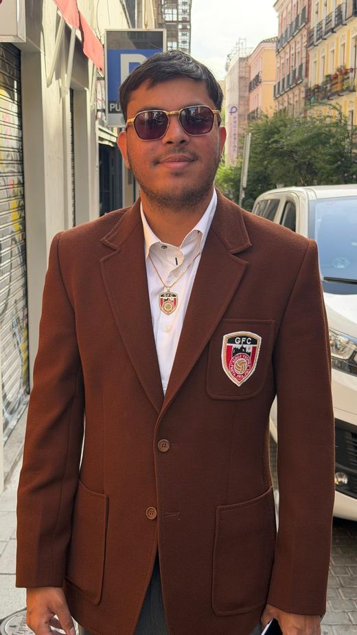 Jai Agarwal on a city street in sunglasses and a brown blazer with the Guarda FC crest